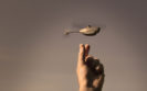 A hand reaching for a mini helicopter